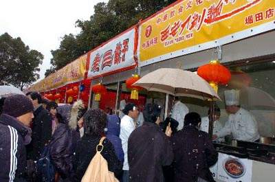 2月9日上午,第二届名古屋中国春节祭在当地久屋大通公园隆重开幕,尽管当天下起了鹅毛大雪,但是众多华侨华人和当地日本民众还是冒雪参加。图为当地日本民众正在冒雪排队品尝中国饺子和刀削面。