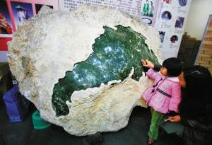 一名小女孩触摸着省博物馆从民间征集到的巨型孔雀石。
